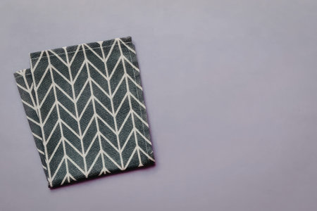 A folded piece of fabric with a dark green and white chevron pattern on a light purple background.