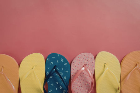 A row of colorful flip flops on a pink background