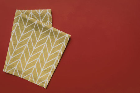 A folded yellow fabric with white pattern on a red background