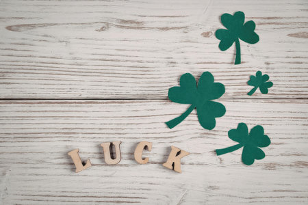 The image features a wooden background with the word 'LUCK' spelled out in wooden letters, accompanied by four green shamrocks of varying sizes.