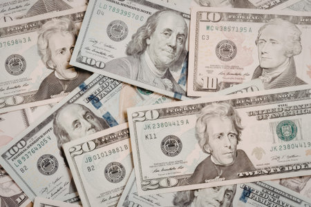 A collection of US dollar bills, predominantly featuring $20 and $50 denominations, with portraits of Benjamin Franklin.