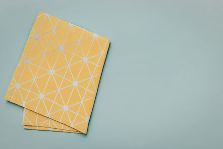 Two yellow cloths with white geometric patterns are placed on a light blue background.