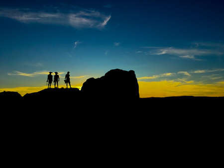 On purpose underexposed view of 3 people -silhouette- standing on a rock during a sunset in Andalusia, Spainの写真素材