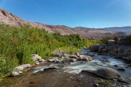 Silk effect on river with vegetation and mountains on the backgroundの写真素材