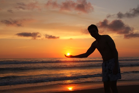 Man holding the sun in his hand  At sunset over the pacific ocean in Ecuador の写真素材