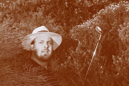 Shocked golfer looking for his golfball in the bushes. Color resembling aged film.の写真素材