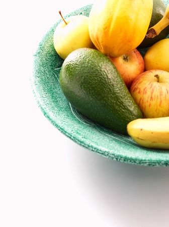 Green bowl of fresh fruit on a white backgroundの写真素材