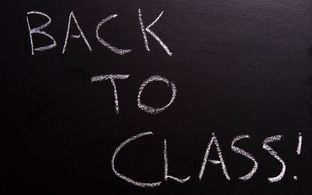 Back to class with an exclamation mark written on a black boardの写真素材
