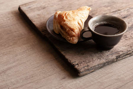 A pie of puff pastry with black coffee on a rustic wooden.の写真素材