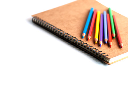 Color pencils and a book on white background.
