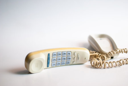 Old telephone with the earphone in the front of the frame, in a perspective view on white background.の写真素材