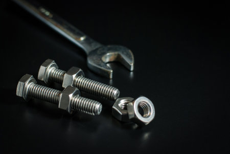 Bolts and nuts with wrench tool on a black background.の写真素材