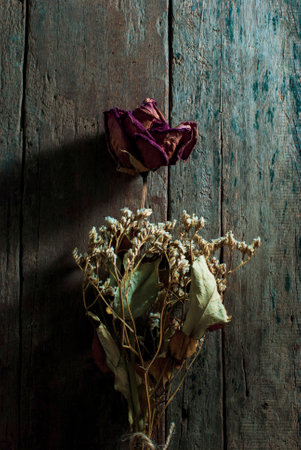 The dried roses are in a dry bouquet on a rustic wooden background.の写真素材