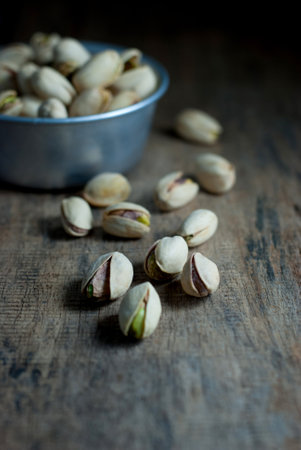 Pistachios that fall on the wood floor and in aluminum cup on the wood floor, selective focus.の写真素材