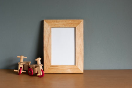Tricycle wooden toy with light wooden frame mockup on wooden table and grey background. blank space,...