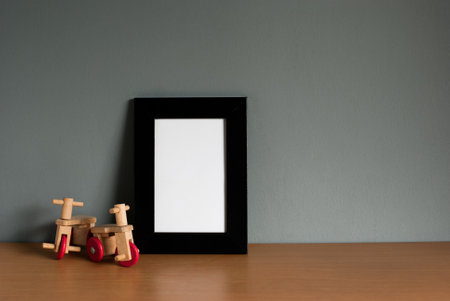 Tricycle wooden toy with black wooden frame mockup on wooden table and grey background. blank space, horizontal image, still life, copy space.の写真素材