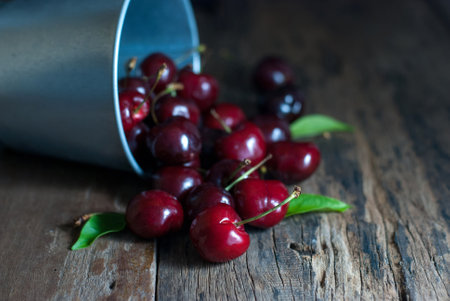 Cherries fruit was poured from the zinc bucket onto the wooden floor.の写真素材