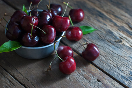 Cherries are placed in the zinc cup and put on a rustic wooden floor, horizontal closeup.の写真素材