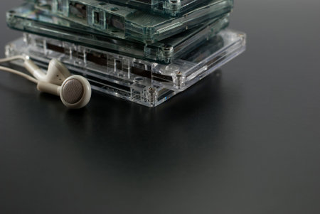 Group of old cassette tapes with earphones on a black floor.