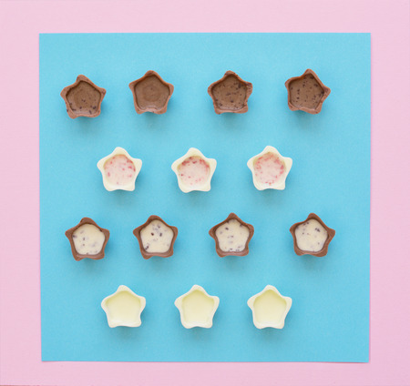 Top view of various chocolate pralines on pink and blue background. Flat lay style.の写真素材