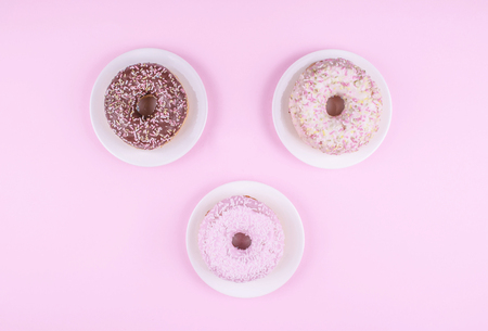 Donut covered with icing in white plate, top view on trendy pink background. Flat lay style.の写真素材
