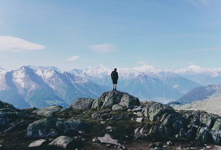 Young man enjoys spectacular view to high mountains. Success, freedom and happiness, achievement in mountains. Active sport concept. Landscape in Alps of Switzerland, Europe.の写真素材