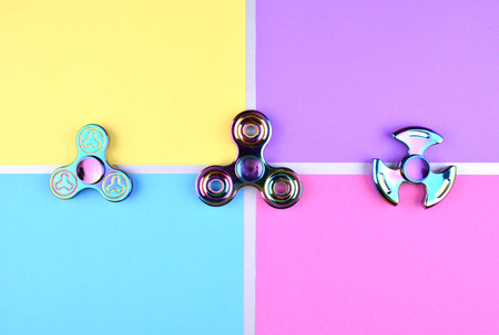 Group of hand fidget spinner toy on colorful and trendy background. Stress and anxiety relief.の写真素材