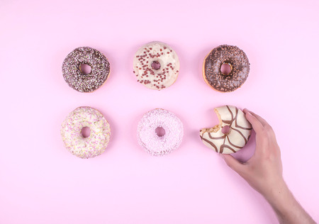 Donut covered with icing in white plate, top view on trendy pink background. Flat lay style.の写真素材