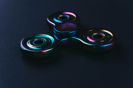 Hand fidget spinner toy on black background. Stress and anxiety relief.の写真素材