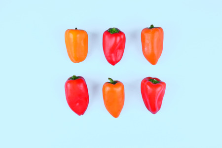 Red, orange, yellow paprika on trendy blue background. Copy space, flat lay style. Colorful diet and healthy food concept.の写真素材