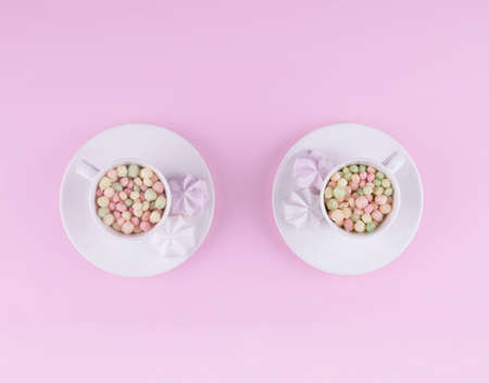 Small pastel color sweeties in a white cup on pink table.の写真素材