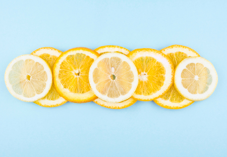 Fresh fruit in a cut on a trendy blue background. Pattern of citrus fruits. Colorful diet and healthy food concept. Flat lay style.の写真素材