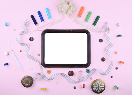 Background with stylish sewing tools and accessories on trendy pink background.