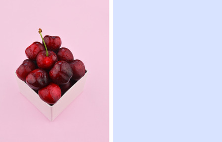 Ripe red sweet cherries on trendy pink background. Flat lay style with place for your text. Colorful diet and healthy food concept.の写真素材