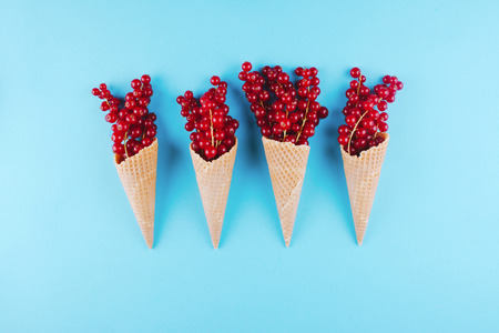 Berries in an ice cream cone on blue background. Flat lay style.