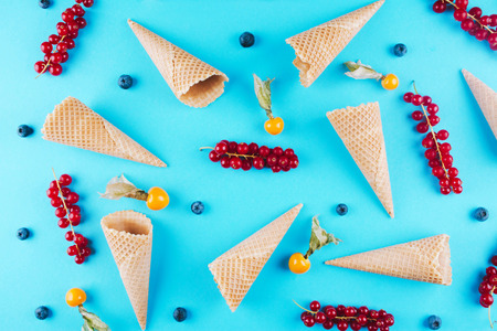 Berries in an ice cream cone on blue background. Flat lay style.