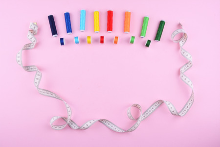 Background with stylish sewing tools and accessories on trendy pink background.