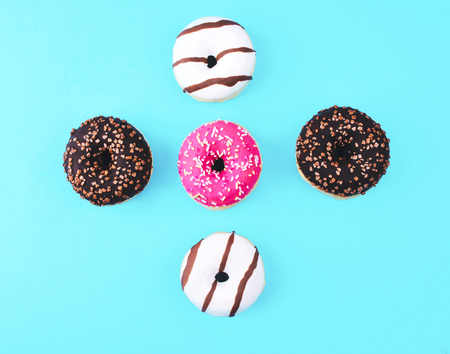 Donut covered with icing, top view on trendy blue background. Flat lay style.