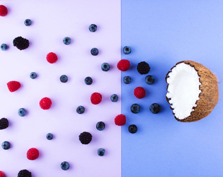 Fruits of coconuts on lilac background with mix of berries. Colorful diet and healthy eating concept. Flat lay style.の写真素材