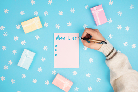 Top view of hands writing a wish list with gifts on a blue background.の写真素材