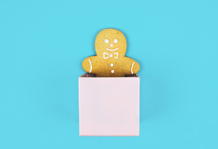 Christmas composition with gingerbread man in a pink box. Flat lay style.
