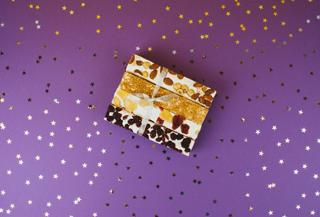 Traditional italian festive torrone or nougat with nuts on lilac background.