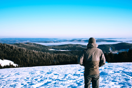Man trekking in mountains in winter. Cold weather, snow on hills, winter hiking.の写真素材