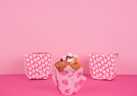 Tasty muffins in colorful paper baking cup with red hearts on pink background.の写真素材