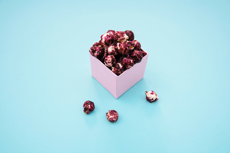 Pink popcorn with berry taste in paper cup on blue background.の写真素材