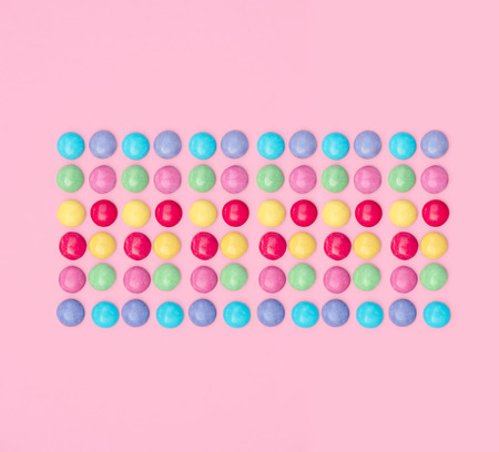 Assorted colored candies on pink background. Flat lay, top view.の写真素材