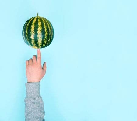 Male hand balancing a watermelon on a finger.の写真素材