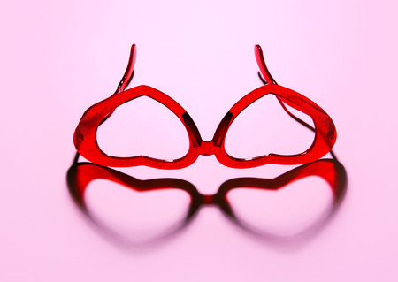 A pair of red heart shaped sun glasses on pink background.の写真素材