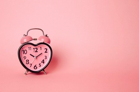 Heart shaped clock on pink background. Valentines day and love and duration concept.の写真素材