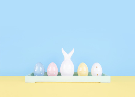 Creative easter composition with painted eggs and easter bunny on yellow and blue background.の写真素材